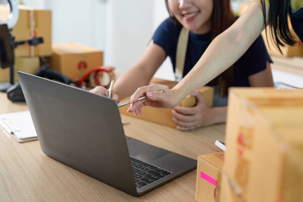 A focused entrepreneur uses a laptop to manage logistics while surrounded by shipping packages, showcasing modern business operations.