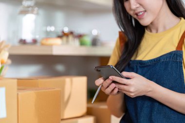 Bir girişimci, nakliye paketlerini yönetirken, iş ortamında modern lojistik ürünleri sergilerken akıllı bir telefonla uğraşır..