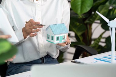 Mimarlar sürdürülebilir inşaat uygulamaları, modern bir ofiste bir model ev ve rüzgar türbini sergilemeyi tartışıyorlar..