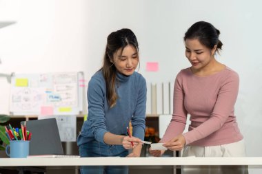 UX ve UI projelerinde işbirliği yapan tasarımcılar, modern ofis ortamında görüşleri ve çizimleri paylaşıyorlar.