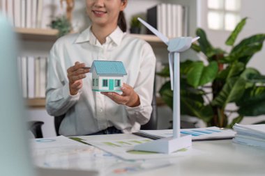 Profesyonel bir model, sürdürülebilir mimari ve tasarımı vurgulayan, çevre dostu bir evin minyatür bir modelini sergiliyor..