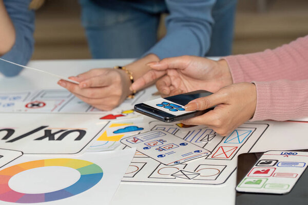 A team collaborating on UX and UI design, using sketches and a smartphone to visualize their ideas and concepts.