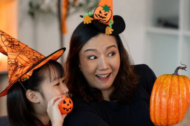 Bir anne ve kız neşeli bir anı paylaşıyor, şenlikli şapkalar takıyor ve balkabağı tutuyor, Cadılar Bayramı 'nı birlikte kutluyorlar..