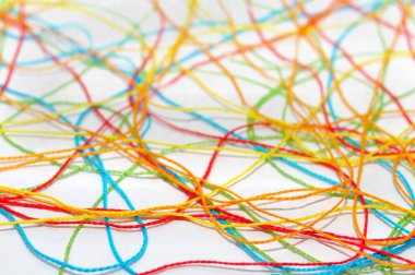 Karışık, çok renkli, beyaz arkaplanda örgü ören ipliklerin seçici odağı