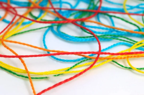 Tangled multicolored knitting threads on a white background
