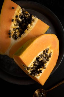 Olgun ve taze kesilmiş papaya. Koyu arkaplanı taze ve tropik meyveler.