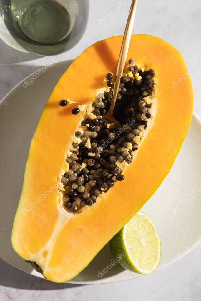 Papaya madura y recién cortada con sus semillas y fondo blanco. Frutas