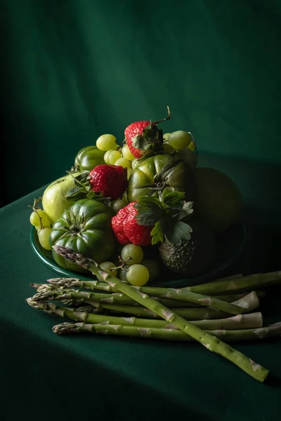 Fruit bowl with fresh green and red fruit. Strawberries, apples, tomatoes, grapes, asparagus... Healthy diet. Food photography with complementary colors