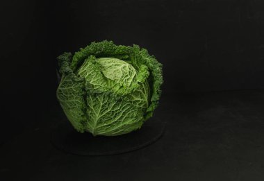 Tahta bir tahta kesme tahtasının üzerinde yeşil bir lahana duruyor. Taze ve çiğ lahana.