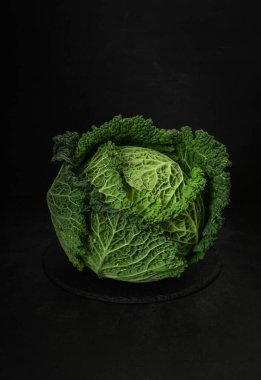 Tahta bir tahta kesme tahtasının üzerinde yeşil bir lahana duruyor. Taze ve çiğ lahana.