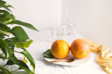 Altın kaşıklı bir tabakta greyfurtlar ve metin için yeri olan beyaz bir arkaplan.