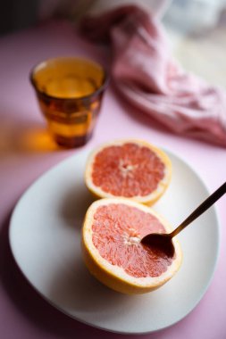 Sağlıklı kahvaltı ya da pembe greyfurtlu atıştırmalık. Pembe ve turuncu tonlarda arkaplan görüntüsü. Meyve, vitamin ve sağlıklı yiyecekler..