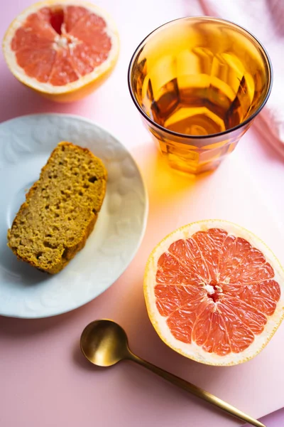 Healthy breakfast or snack with pink grapefruit and homemade cake. Background image with pink and orange tones. Fruit, vitamins, and homemade food.