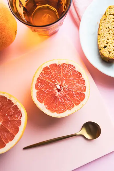 Healthy breakfast or snack with pink grapefruit and homemade cake. Background image with pink and orange tones. Fruit, vitamins, and homemade food.
