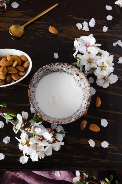 Almond milk with almonds and almond blossoms on the table: the vegan alternative to traditional milk