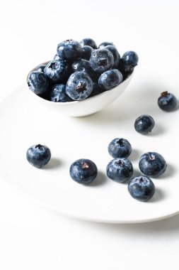 Beyaz arka planda beyaz bir kasede taze yaban mersini, mesaj için yer var.