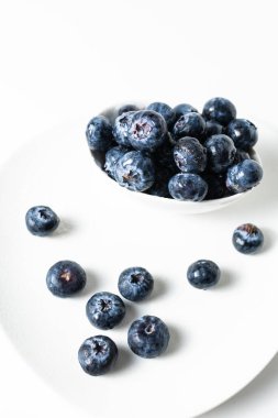 Beyaz arka planda beyaz bir kasede taze yaban mersini, mesaj için yer var.