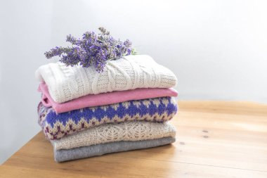 Beyaz arka planda taze lavanta buketi ile kaplanmış renkli örgü süveter yığını, metin için yer var..