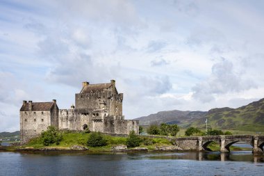 Loch Duich tarafındaki Eilean Donan Kalesi manzaralı, yemyeşil ve sakin bir göl ile çevrili.