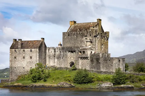 stock image Scenic view of Eilean Donan Castle by Loch Duich, surrounded by lush greenery and a calm lake