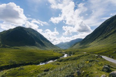 Bereketli, yemyeşil Glencoe Vadisi 'nde, arka planda yüksek dağlar olan sakin bir nehir esiyor..