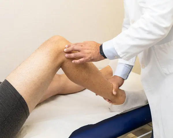Bir travmatolog klinik konsültasyonda bir hastaya diz muayenesi yapıyor..