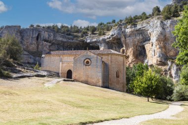 İspanya, Soria 'da kayalık kayalıklar ve yeşilliklerle çevrili Rio Lobos Kanyonu manzarasına yerleştirilmiş tarihi bir taş şapel..