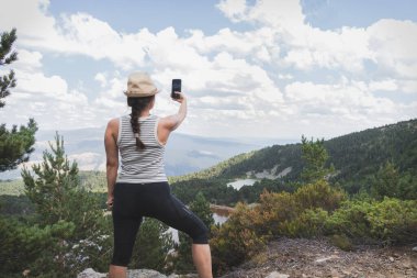 Bir kadın akıllı telefonuyla Soria, İspanya 'daki Neila Gölü' nde fotoğraf çekiyor..