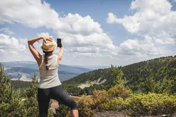 stock image A woman captures a selfie with her smartphone at the Neila Lagoons overlook in Soria, Spain.