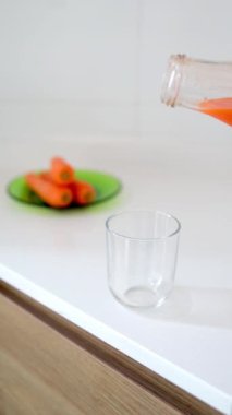 Bu dikey videoda bardağa taze ve sağlıklı havuç suyu dökülüyor. Besleyici bir destek için mükemmel