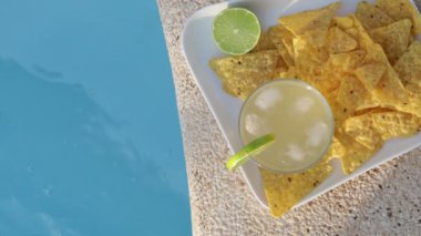 Havuz kenarında nachos eşliğinde limonlu zencefilli kombu çayı, mükemmel bir yaz gününün özünü yakalıyor.