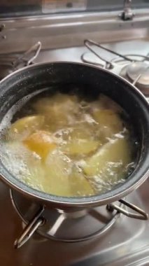 Konforlu bir karavanın mutfağındaki ocakta kaynayan patateslerin, kamyonetin pişirilmesinin özünü yakaladığı dikey bir video..