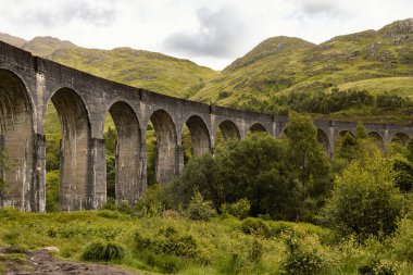 Harry Potter filmlerindeki rolüyle tanınan Glenfinnan Viyadükünün çarpıcı bir görüntüsü, Jakobit Buhar Treni 'nin 21 kemerinin üzerinden geçmesiyle, İskoç Highlands' ın güzel arka planına karşı kurulmuştur.