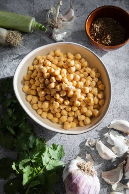 Mutfak tezgahına konmuş taze bezelye, otlar ve baharatlar da dahil olmak üzere ev yapımı falafel yapmaya hazır taze malzemeler.