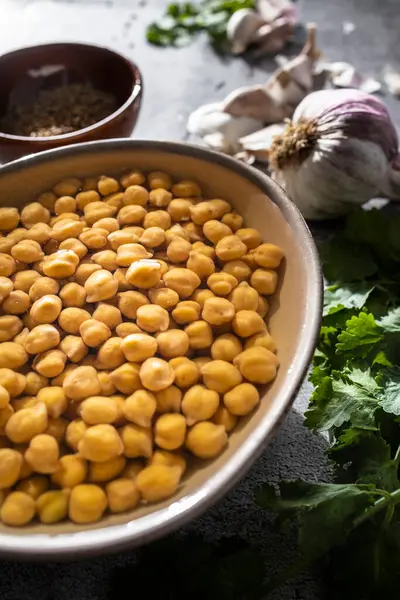 Mutfak tezgahına konmuş taze bezelye, otlar ve baharatlar da dahil olmak üzere ev yapımı falafel yapmaya hazır taze malzemeler.
