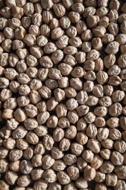 Kurumuş bezelyelerin detaylı yakın çekimi doğal dokusunu ve yumuşak ışık altında toprak tonunu gösteriyor.