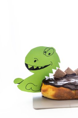 Homemade dinosaur-shaped orange cake with chocolate ganache, set on a white background with ample space for text, ideal for kids' birthday themes clipart