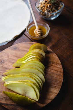 Bir galet için, armut, şam fıstığı, peynir, bal ve hamur hamuru gibi malzemelerle dolu, sade, ahşap bir masa üzerinde, sıcak ışıklandırmalı, güzel bir yaşam..