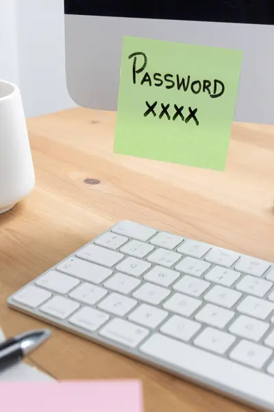 Bir bilgisayar ekranına giriş bilgilerini gösteren yapışkan bir notun yerleştirildiği bir işyeri ortamı, güvenlik ihmalkarlığını ve potansiyel siber tehditleri vurguluyor