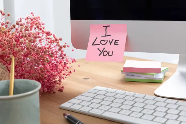 Sevgi, şefkat ve dijital romantizmi sembolize eden el yazısıyla yazılmış bir mesajı içeren yapışkan bir notla bilgisayar ekranının yürek ısıtan bir görüntüsü..