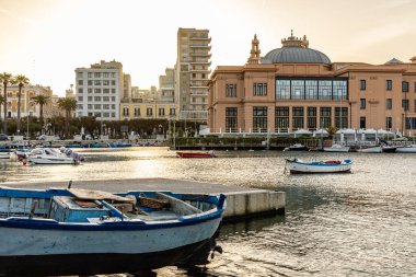 Puglia, Bari 'deki Porto Vecchio üzerinde nefes kesici bir günbatımı, tarihi balıkçı teknelerine sıcak altın renkler dökmek ve Adriyatik sularını sakinleştirmek
