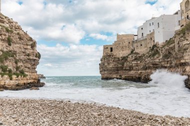 Polignano a Mare, Puglia, İtalya 'daki Lama Monachile plajının çarpıcı manzarası. Turkuaz suları, kayalık uçurumları ve büyüleyici eski kasaba atmosferiyle ünlüdür..
