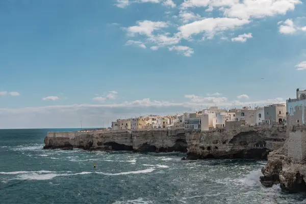 Polignano a Mare, Puglia sahilinin manzarası, beyaz binalar, kayalık kayalıklar ve güney İtalya 'nın berrak mavi sularını gösteriyor..