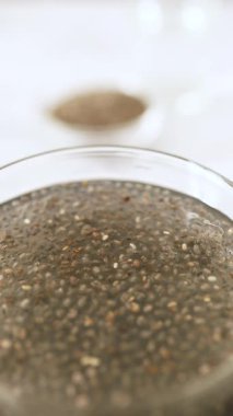 Chia tohumlarının suda asılı ve genişlediğini gösteren dikey video doğal jel dokusunu vurguluyor..