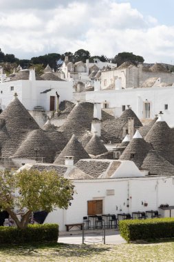 Güney İtalya, Alberobello 'daki Trulli mahallesinin geniş panoramik bir görüntüsü, konik taştan çatıları olan beyazlatılmış yoğun ev kümelerini yakalıyor.