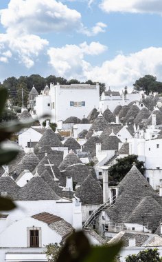 Güney İtalya, Alberobello 'daki Trulli mahallesinin geniş panoramik bir görüntüsü, konik taştan çatıları olan beyazlatılmış yoğun ev kümelerini yakalıyor.