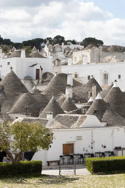 Güney İtalya, Alberobello 'daki Trulli mahallesinin geniş panoramik bir görüntüsü, konik taştan çatıları olan beyazlatılmış yoğun ev kümelerini yakalıyor.