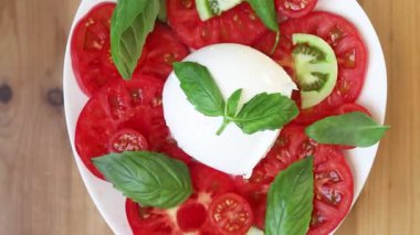 Canlı yeşil fesleğenli taze ve renkli mozzarella salatasını gösteren yakın plan bir video.