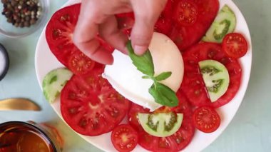 Canlı yeşil fesleğenli taze ve renkli mozzarella salatasını gösteren yakın plan bir video.