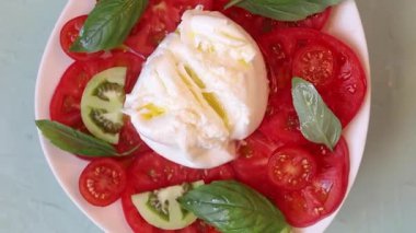 Canlı yeşil fesleğenli taze ve renkli mozzarella salatasını gösteren yakın plan bir video.